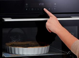 Person pressing the touch controls of a built-in oven